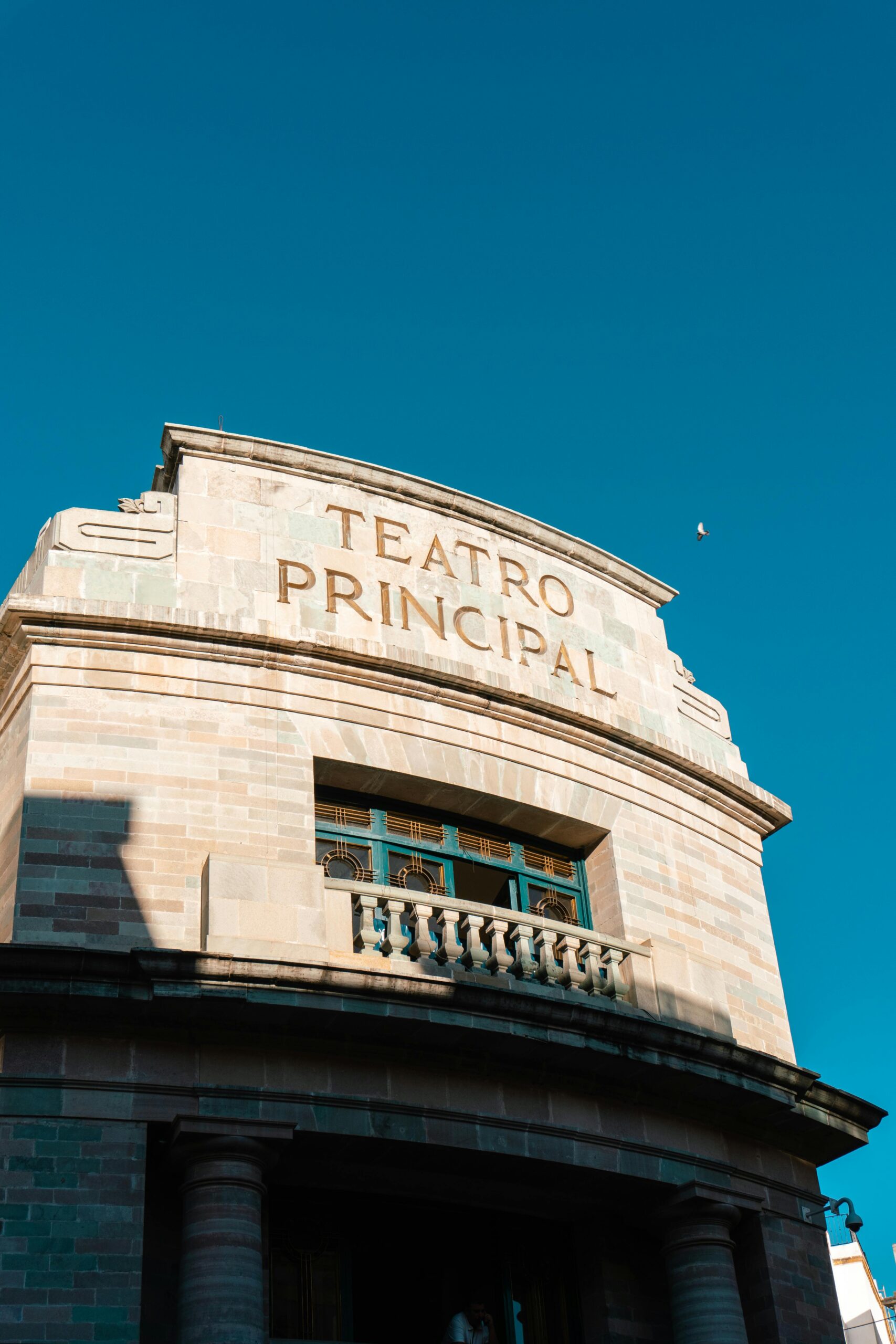 Historic Teatro Principal in Guanajuato, Mexico against a vivid blue sky with architectural detail.
